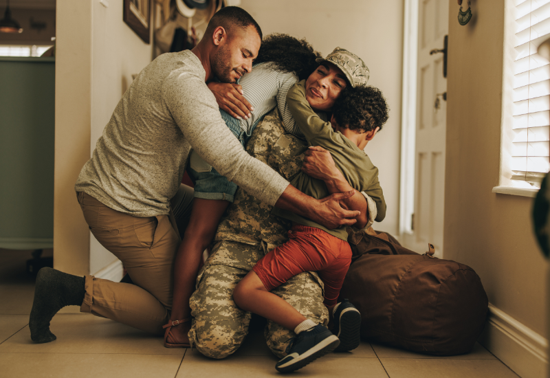 Woman in military uniform hugging family