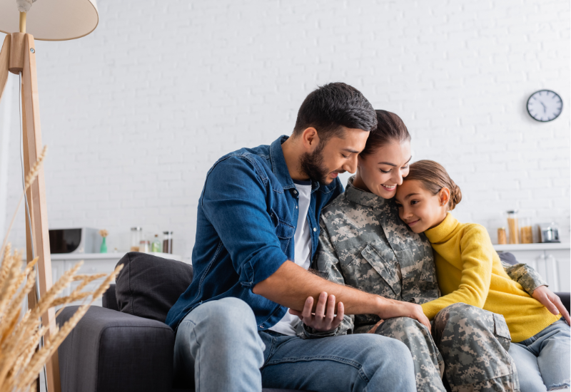 Woman in military uniform hugging family